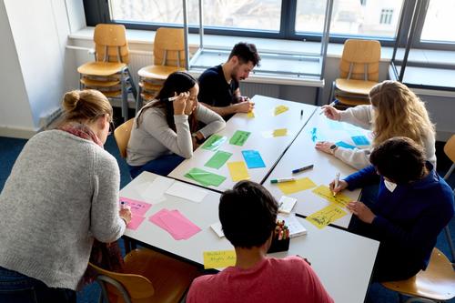 Workshoteilnehmer:innen schreiben auf Moderationskarten / Participants writing on moderation cards at the workshop